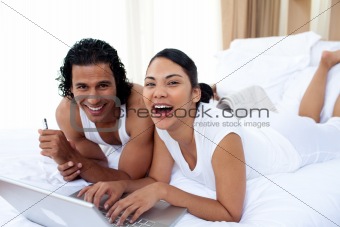 Couple using a laptop lying on the bed