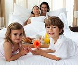 Smiling family having breakfast in the bedroom