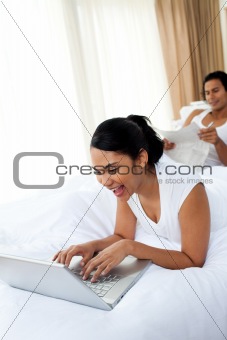 A woman using a laptop lying on the bed