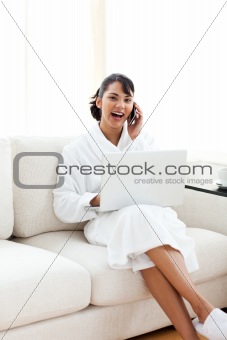 Smiling woman on phone using a laptop 