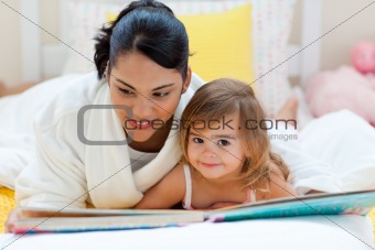 Cute little girl reading a book with her mother 