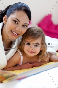 Close-up of a beautiful little girl and her mother reading a boo