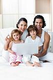 Young family using a laptop on the bed 