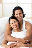 Attractive man hugging his wife lying on the bed