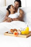 Smiling lovers having breakfast on the bed 