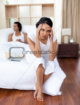 Angry couple sitting separately on their bed after an argument