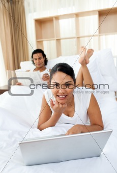 Attractive woman lying on the bed using a laptop 