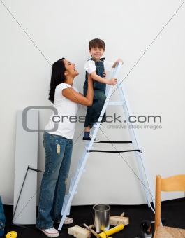 Smiling little boy climbing a ladder while renovating a room