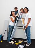 Merry parents with their children painting a room in their house