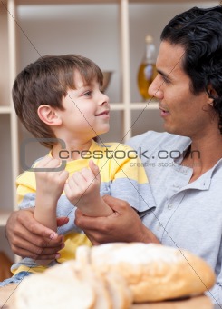 Cute little boy and his father cutting bread