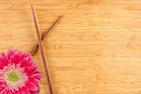 Pink Gerber Daisy and Chopsticks on a Bamboo Background with Copy Space.