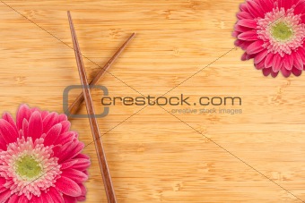 Pink Gerber Daisy and Chopsticks on a Bamboo Background with Copy Space.
