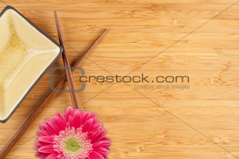 Gerber Daisy, Chopsticks and Dish on a Bamboo Background with Copy Space.