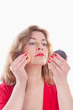 middle-aged woman in red putting on makeup - isolated on white