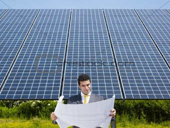 businessman standing near solar panels
