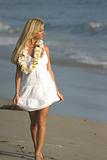 Beautiful Blond walking on the beach in a White dress and a Lei.