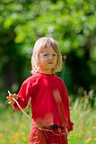 boy with long blond hair and grass straw in the garden