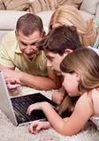 Domestic family of four lying and working with laptop