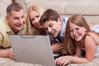 Domestic family lying in living room with lap top