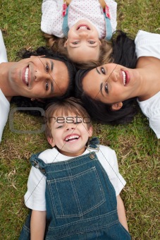 Little boy lying in a circle with his family in a park