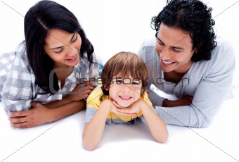 Happy little boy lying on the floor with his parents against a white background