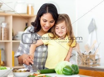 Blond child cutting vegetables with her mother