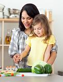 Brunette mother helping her daughter prepare salad in the kitchen