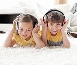 Smiling siblings listening music with headphones