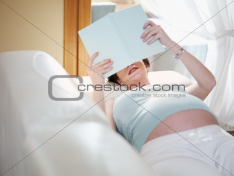 pregnant woman reading book at home