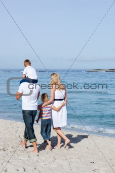 Cheerful family walking on the sand 