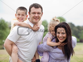 Smiling couple carrying kids on their back