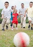 Beautiful family of five on outdoors running towards the foot ball