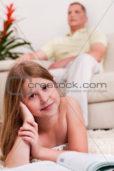Young little girl lying with her book in living room