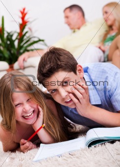 Two young kids lying with a book in living room