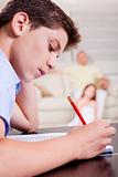 Young teenager writing in his notebook in living room 