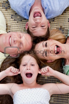 Happy family of four lying on the carpet with their heads together