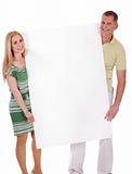 Middle aged smiling couple holding a blank white board