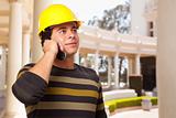 Handsome Hispanic Contractor with Hard Hat Talking on His Cell Phone.