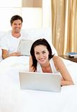 Woman using her laptop and man reading newspaper