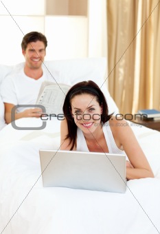 Woman using her laptop and man reading newspaper