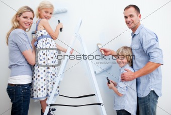 Happy family painting a room with brushes