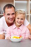 Happy little girl eating fruit with her father 