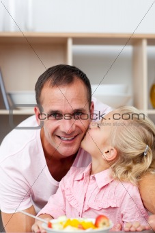 Cute little girl eating fruit with her father 