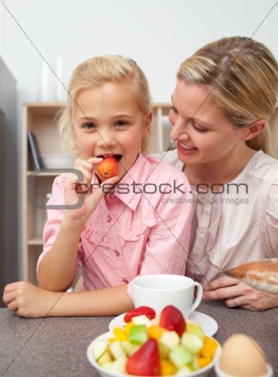 Attractive mother eating fruit with her daughter 