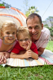 Happy father and his children lying on the grass 