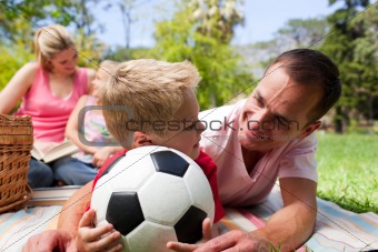 Father and son holding a soccer ball with their family reading i