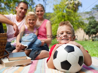 Little boy having fun with a soccer ball with his family smiling