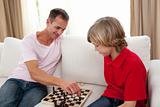Attentive father playing chess with his son 