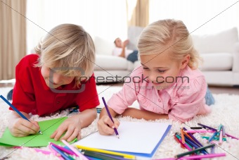 Concentrated children drawing lying on the floor 