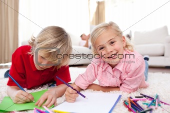 Cheerful children drawing lying on the floor
